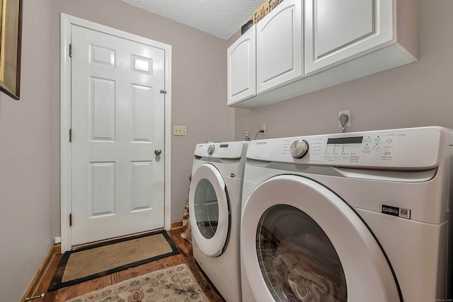 laundry area featuring a textured ceiling, washing machine and dryer, dark hardwood / wood-style floors, and cabinets