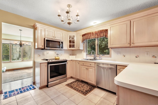 kitchen featuring backsplash, light tile patterned floors, stainless steel appliances, decorative light fixtures, and a chandelier