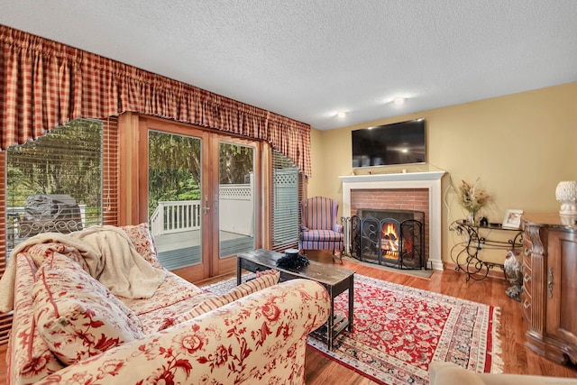 living room featuring wood-type flooring, a textured ceiling, and a fireplace