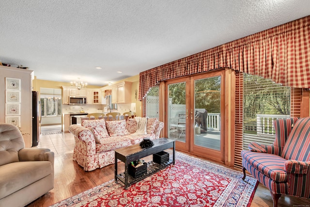 living room with a textured ceiling, light wood-type flooring, and a chandelier