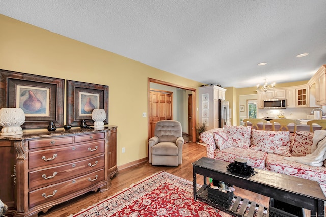 living room with a textured ceiling, light hardwood / wood-style flooring, and a chandelier