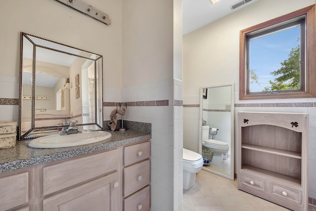 bathroom featuring tile walls, vanity, toilet, and tile patterned floors