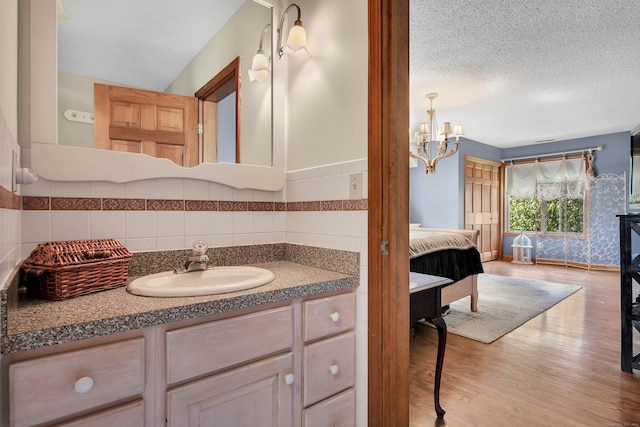 bathroom featuring wood-type flooring, vanity, tile walls, and a textured ceiling