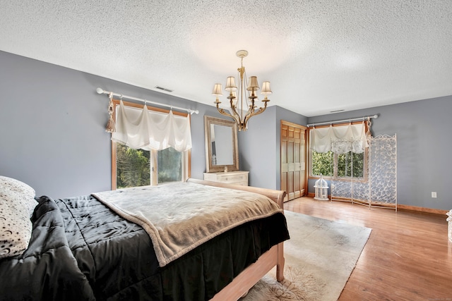 bedroom featuring a textured ceiling, a notable chandelier, and hardwood / wood-style flooring