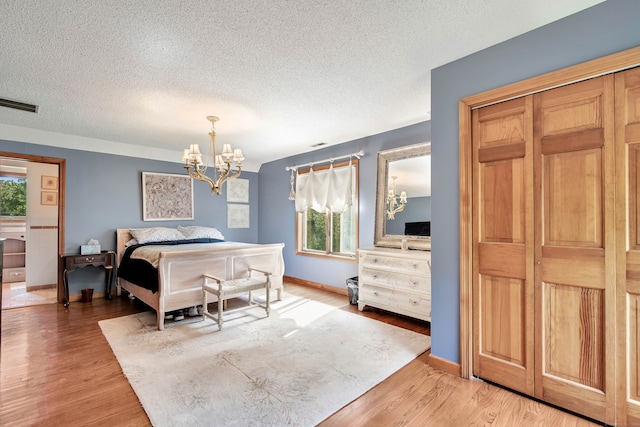 bedroom with multiple windows, a textured ceiling, a notable chandelier, and hardwood / wood-style flooring