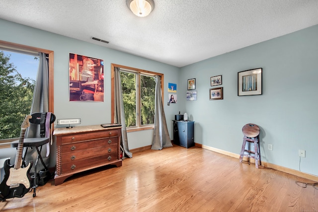 interior space featuring light wood-type flooring and a textured ceiling