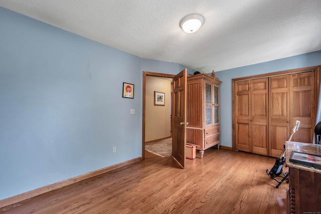 unfurnished bedroom featuring a textured ceiling, a closet, and light hardwood / wood-style floors