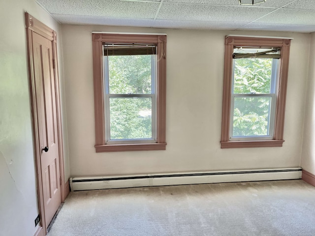 carpeted spare room featuring baseboard heating and a drop ceiling