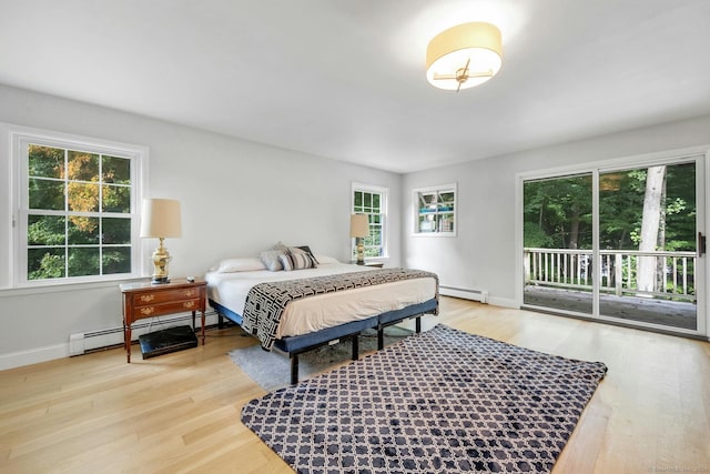 bedroom with baseboard heating, light wood-type flooring, and access to exterior