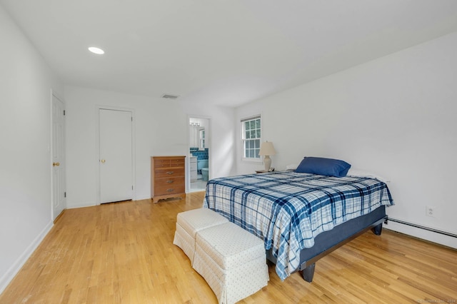 bedroom with a baseboard radiator, wood-type flooring, and ensuite bath