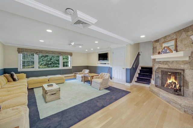 living room featuring ceiling fan, a fireplace, crown molding, and light hardwood / wood-style floors