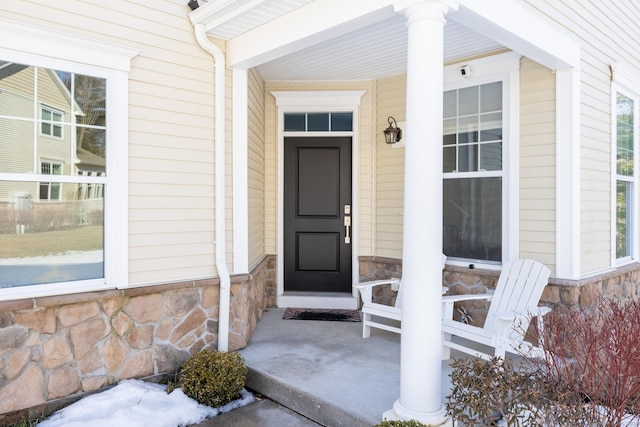 property entrance featuring stone siding and covered porch