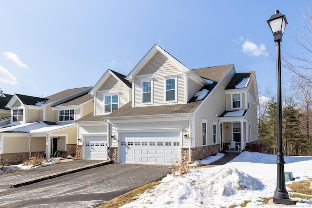 view of front facade with a garage, stone siding, and aphalt driveway