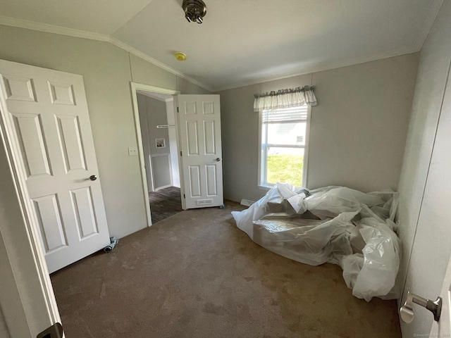 bedroom with dark colored carpet, vaulted ceiling, and crown molding