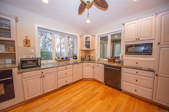 kitchen with stone counters, light hardwood / wood-style floors, black appliances, and backsplash