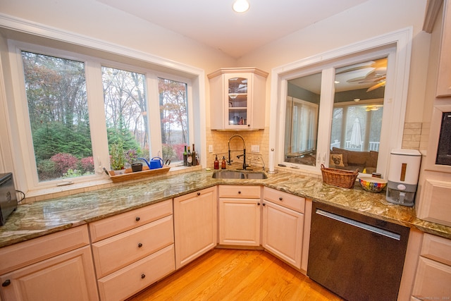 kitchen featuring sink, light wood-type flooring, stainless steel dishwasher, light stone counters, and decorative backsplash