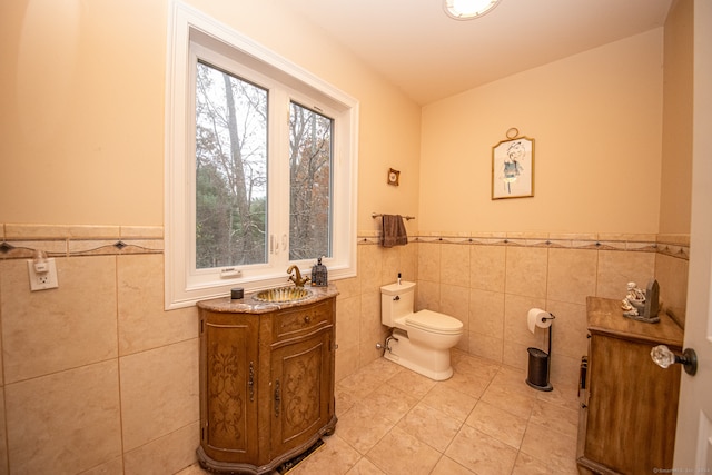 bathroom featuring toilet, vanity, tile patterned floors, and tile walls