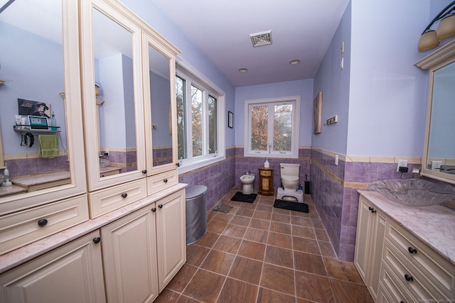 bathroom featuring toilet, tile walls, vanity, a bidet, and tile patterned flooring