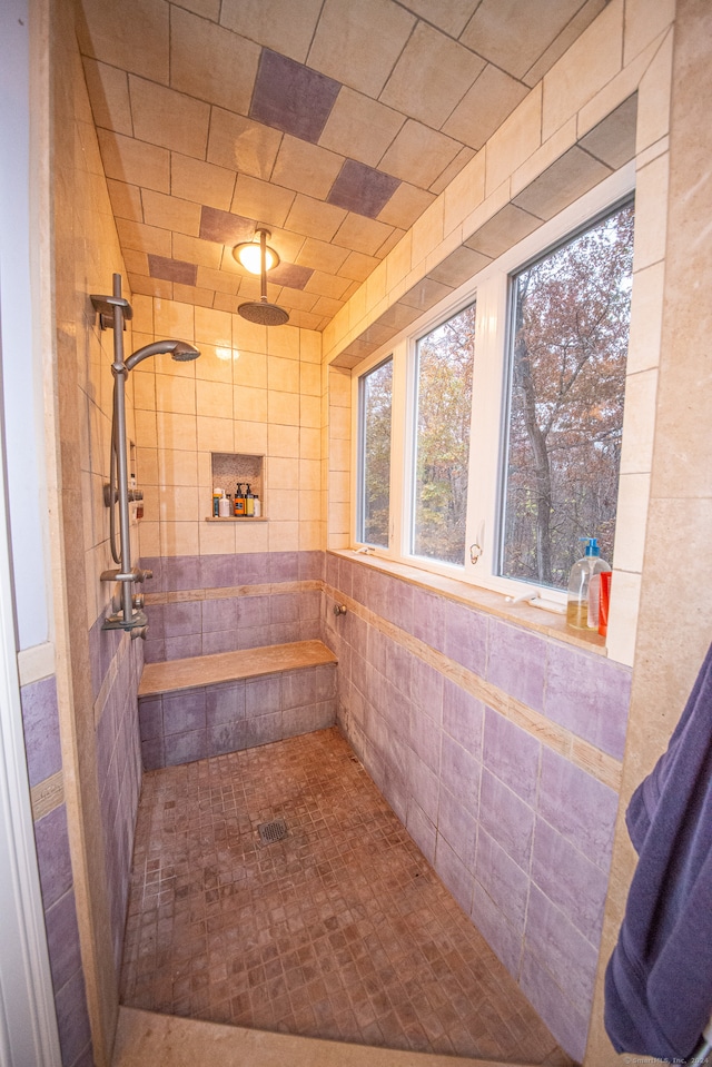 bathroom with a tile shower and tile walls