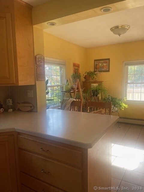 kitchen with baseboard heating, kitchen peninsula, and light tile patterned floors