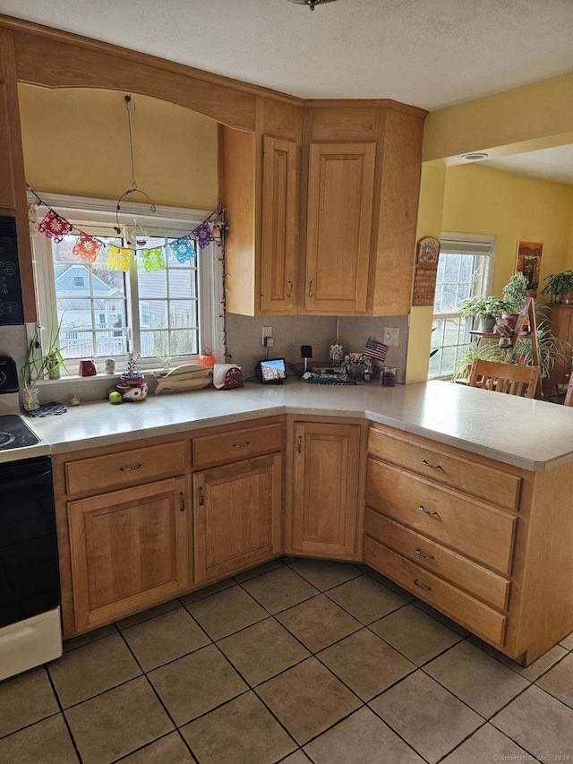 kitchen with decorative light fixtures, a healthy amount of sunlight, kitchen peninsula, and white stove