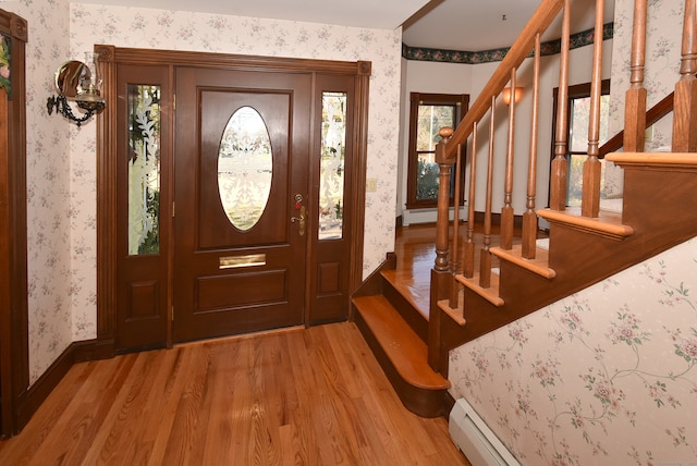 entryway with wood-type flooring, a baseboard heating unit, and a healthy amount of sunlight