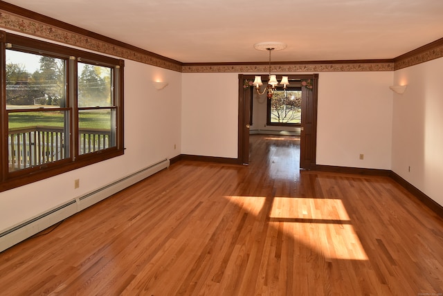 empty room featuring hardwood / wood-style flooring, ornamental molding, baseboard heating, and an inviting chandelier