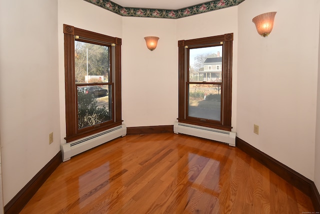 empty room featuring wood-type flooring and baseboard heating