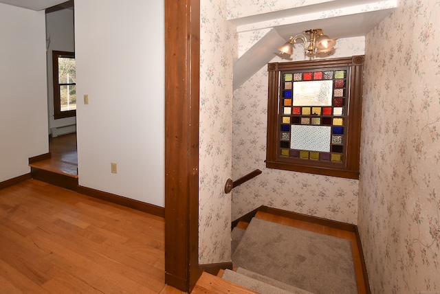 stairway featuring hardwood / wood-style floors, an inviting chandelier, and a baseboard radiator