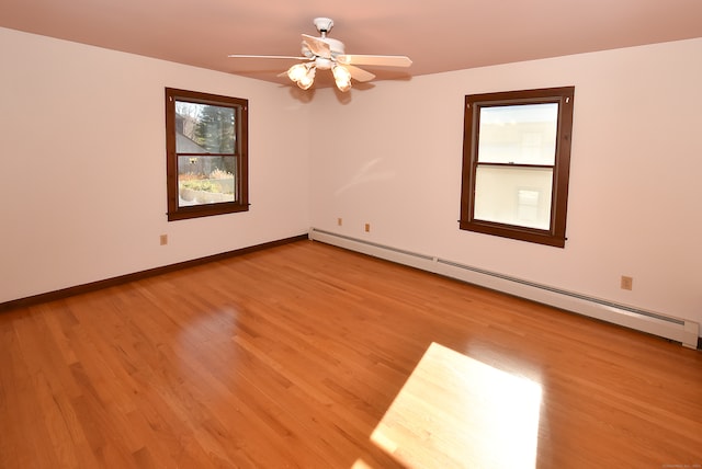 spare room featuring light hardwood / wood-style flooring, ceiling fan, and a baseboard heating unit