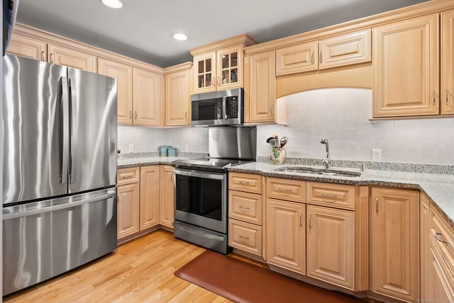 kitchen featuring light hardwood / wood-style flooring, backsplash, sink, appliances with stainless steel finishes, and light stone counters