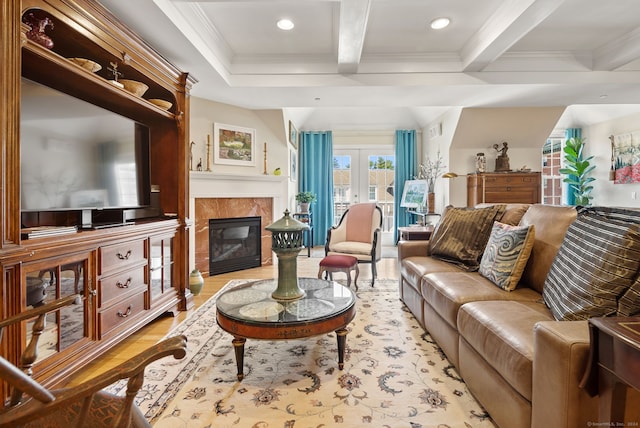 living room featuring a fireplace, french doors, beamed ceiling, ornamental molding, and light hardwood / wood-style flooring