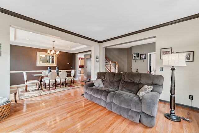 living room with crown molding, a tray ceiling, hardwood / wood-style floors, and a notable chandelier