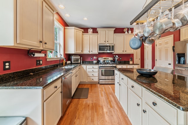 kitchen with dark stone counters, light hardwood / wood-style floors, appliances with stainless steel finishes, and sink