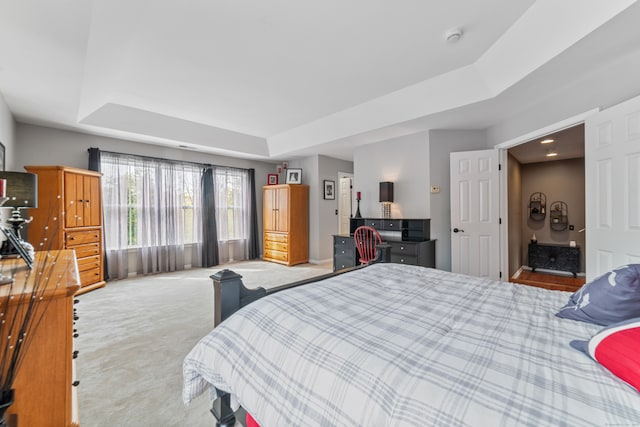 bedroom featuring a tray ceiling and light colored carpet