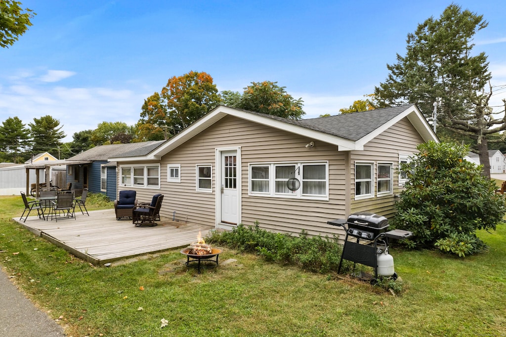 12 N St, Madison, CT 06443 - rear view of property featuring a lawn, roof with shingles, a wooden deck, and an outdoor fire pit