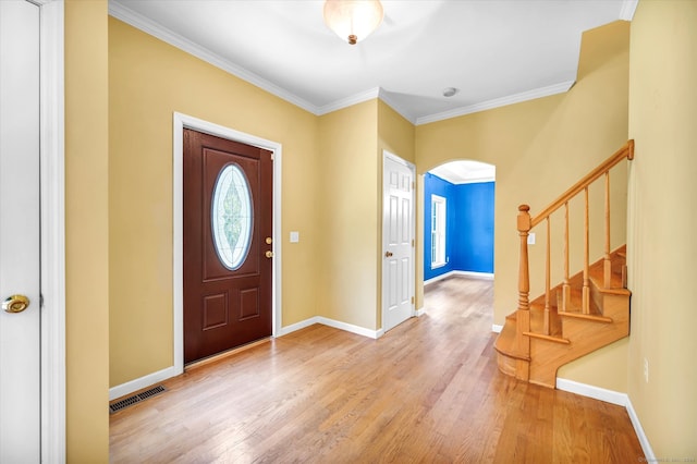 foyer with light wood-type flooring and crown molding