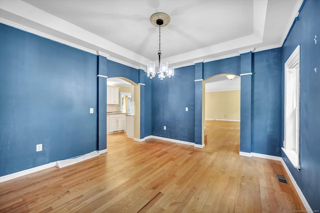 unfurnished room featuring hardwood / wood-style flooring, a tray ceiling, crown molding, and a chandelier