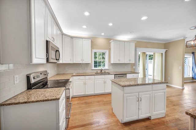 kitchen featuring white cabinetry, a center island, stainless steel appliances, and a wealth of natural light