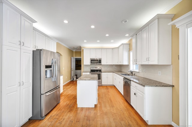 kitchen featuring stainless steel appliances, white cabinets, stone counters, and a kitchen island