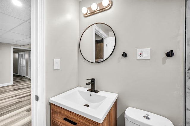 bathroom featuring a paneled ceiling, vanity, toilet, and hardwood / wood-style flooring