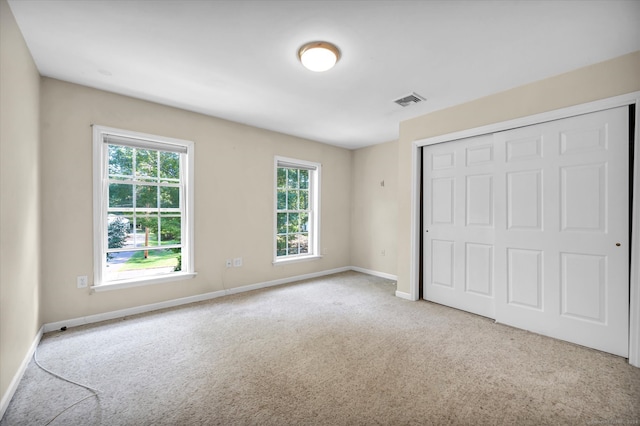 unfurnished bedroom featuring light carpet and a closet