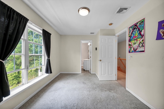 unfurnished bedroom featuring ensuite bath and light carpet