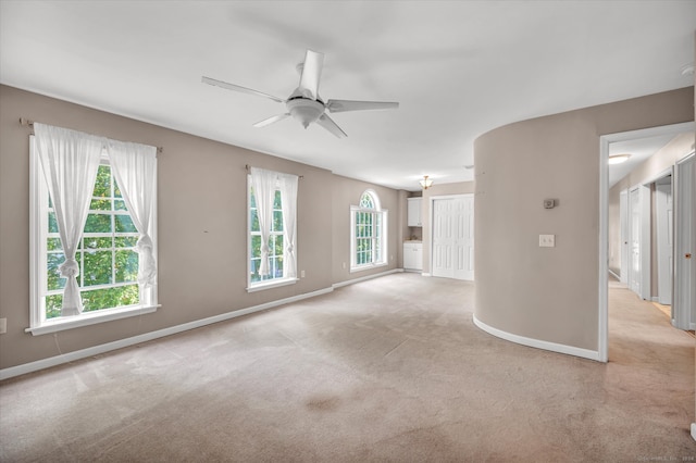 carpeted spare room featuring ceiling fan and a healthy amount of sunlight