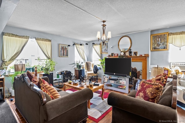 living room featuring a notable chandelier, wood-type flooring, a textured ceiling, and plenty of natural light