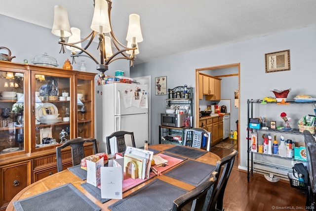 dining space featuring a textured ceiling, dark wood-type flooring, and a notable chandelier