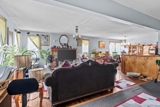 living room with an inviting chandelier, hardwood / wood-style flooring, plenty of natural light, and a textured ceiling