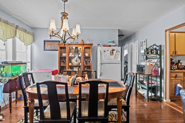 dining room featuring an inviting chandelier, a textured ceiling, and dark hardwood / wood-style floors