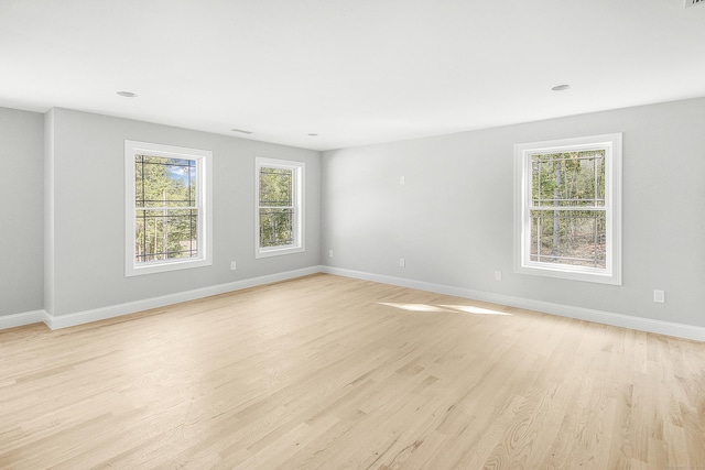 spare room featuring light hardwood / wood-style flooring and a healthy amount of sunlight