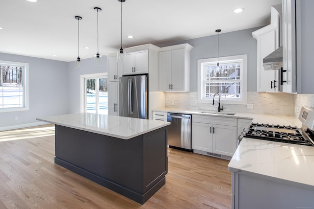 kitchen with a kitchen island, appliances with stainless steel finishes, pendant lighting, sink, and white cabinets